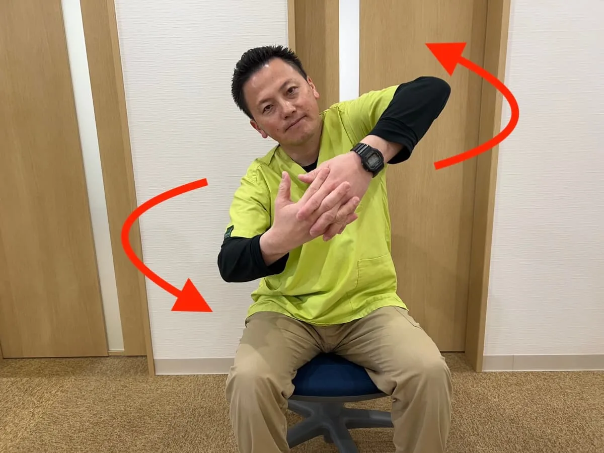 体の前で腕の輪を作るストレッチの実演